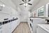 Modern laundry room with sleek white washers and dryers, ample natural light, and elegant wood flooring.