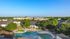 Aerial view of a vibrant apartment community featuring lush greenery and a stunning lagoon-style swimming pool, surrounded by modern residential buildings under a clear blue sky.