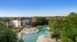 Beautiful apartment complex featuring a luxurious pool area with modern lounge chairs and lush greenery, under a clear blue sky.