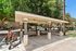 Charming outdoor gazebo with benches, surrounded by lush greenery and electric scooters, offering a scenic and convenient rest area.