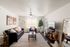 Inviting living room with chic decor, featuring a modern black sofa, elegant floor lamp, and cozy armchair. Bright and airy with a large window, stylish coffee table, and tasteful wall art.