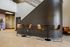 Elegant modern seating area featuring stylish bar stools and sleek tables against a curving staircase backdrop, perfect for social gatherings in a contemporary apartment setting.