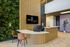 Chic and modern reception area of 865 East Residences featuring a stylish curved wooden desk, vibrant green living wall, and sleek neutral decor.