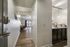 Inviting apartment hallway leading to a bright living room with cozy seating, adjacent to a modern kitchen featuring sleek cabinetry and elegant lighting.
