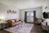 Modern living room with sleek brown leather furniture, stylish decor, and a cozy ambiance, featuring large windows and a wall-mounted flat-screen TV.
