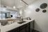 Sleek modern kitchen with elegant pendant lighting, shiny countertops, and an open-concept view into the inviting living area. Perfect for stylish urban living.