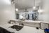 Modern open-concept kitchen with sleek countertops, cozy living area, and stylish decor, illuminated by chic pendant lighting.