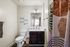 Modern bathroom featuring a sleek white countertop, elegant dark wood vanity, stylish shower curtain, and cozy wall decor.