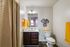 Bright and modern bathroom featuring elegant fixtures, dark wood vanity, chic wall decor, and vibrant yellow towels.