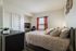 Cozy bedroom with elegant bedding, bright window with sheer curtains, and a stylish workspace for productivity.