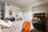 Cozy bedroom with modern decor, featuring a chic desk setup and inviting orange accents.