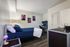 Modern bedroom with sleek wooden flooring, elegant art pieces, and a comfortable bed, complemented by a stylish workspace.