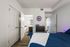 Inviting bedroom with modern decor, featuring a sleek wooden floor, cozy bed, and en-suite bathroom entrance.
