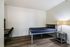 Modern minimalist bedroom with sleek hardwood floors, a comfortable bed, a stylish desk, and abundant natural light.