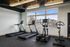 Modern fitness center with sunlight-filled space, featuring treadmills, elliptical, and stationary bike for an invigorating workout experience.
