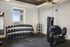Modern fitness room with a wide range of dumbbells, kettlebells, and professional workout equipment, illuminated by natural light through large windows.