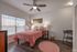 Charming bedroom with cozy pink bedding, stylish decor, and natural light from large windows.
