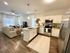 Modern open-concept kitchen and living room with sleek white cabinets, stainless steel appliances, and cozy seating area.