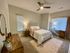 Elegant bedroom with cozy decor, featuring a plush bed, stylish wooden furniture, and ample natural light.