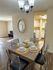 Inviting dining area with elegant table setting and stylish chandelier, leading to a modern kitchen with stainless steel appliances.