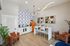 Contemporary kitchen and dining area with bold geometric tile accent, white cabinetry, vibrant orange fridge, and modern lighting.