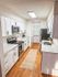Bright and modern kitchen with sleek stainless steel appliances, elegant white cabinetry, and warm wood flooring, creating a welcoming and functional space.