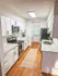 Contemporary kitchen featuring sleek white cabinetry, stainless steel appliances, and elegant wooden flooring.