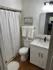 Elegant bathroom featuring modern fixtures, a pristine shower curtain, and a stylish vanity with a sleek marble countertop.