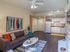 Inviting open-concept living room and kitchen with modern decor, featuring a cozy sofa, vibrant artwork, and sleek cabinetry.