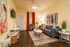 Cozy living room with modern decor, vibrant artwork, and comfortable seating featuring a stylish sofa, accent chair, and decorative rugs.