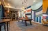 Modern recreation room featuring a sleek pool table, chic pendant lighting, and vibrant geometric wall art. Cozy seating and a bookshelf add a touch of sophistication.