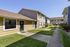 Charming apartment complex featuring well-maintained green lawns, modern exterior design, and sunny communal walkways.
