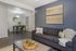 Modern living room with a sleek grey sofa, elegant wall art, and a cozy dining area with contemporary decor.