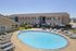 Inviting apartment community featuring a sparkling oval pool, surrounded by comfortable lounge chairs and a well-maintained landscape.