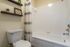 Modern bathroom featuring a pristine white bathtub, elegant shower curtain, and stylish wooden shelves adorned with decor.