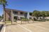Charming apartment complex with well-maintained landscaping, palm trees, and ample parking under a clear blue sky.