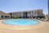 Beautiful community pool surrounded by lounge chairs and landscaped gardens, enhancing the sunny apartment complex setting.