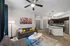 Modern open-concept living room and kitchen with stylish decor, vibrant artwork, and sleek stainless steel appliances.