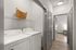 Modern apartment laundry area with stylish white washer and dryer, sleek shelving, and elegant wood flooring.