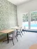 Bright and inviting dining area with modern green patterned accent wall, overlooking a sparkling outdoor pool.