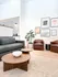 Bright and modern living room featuring a sleek sofa, elegant coffee tables, stylish armchairs, and contemporary wall art for a welcoming atmosphere.