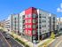Modern apartment building with vibrant red accents, offering contemporary living spaces and balconies on a sunny urban street.