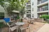 Inviting apartment courtyard with modern outdoor seating, lush greenery, and convenient grilling stations for social gatherings.