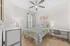 Bright and modern bedroom with stylish ceiling fan, featuring a cozy bed, elegant side tables, and chic wall art.