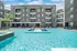 Modern apartment complex with a luxurious pool, sun loungers, and outdoor seating, creating an inviting oasis for residents.