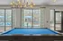 Luxurious apartment recreation room featuring a sleek billiards table and large windows with a view of a sparkling pool area.