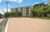 Modern apartment complex with a spacious outdoor sand volleyball court and stylish seating area surrounded by lush greenery.