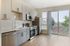 Contemporary kitchen with sleek cabinetry, stainless steel appliances, and abundant natural light from large windows and balcony access.