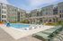 Modern apartment complex with inviting outdoor pool area featuring stylish loungers and vibrant community space.