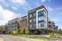 Modern apartment building with sleek architectural design, featuring large windows and vibrant landscaping, under a clear blue sky.